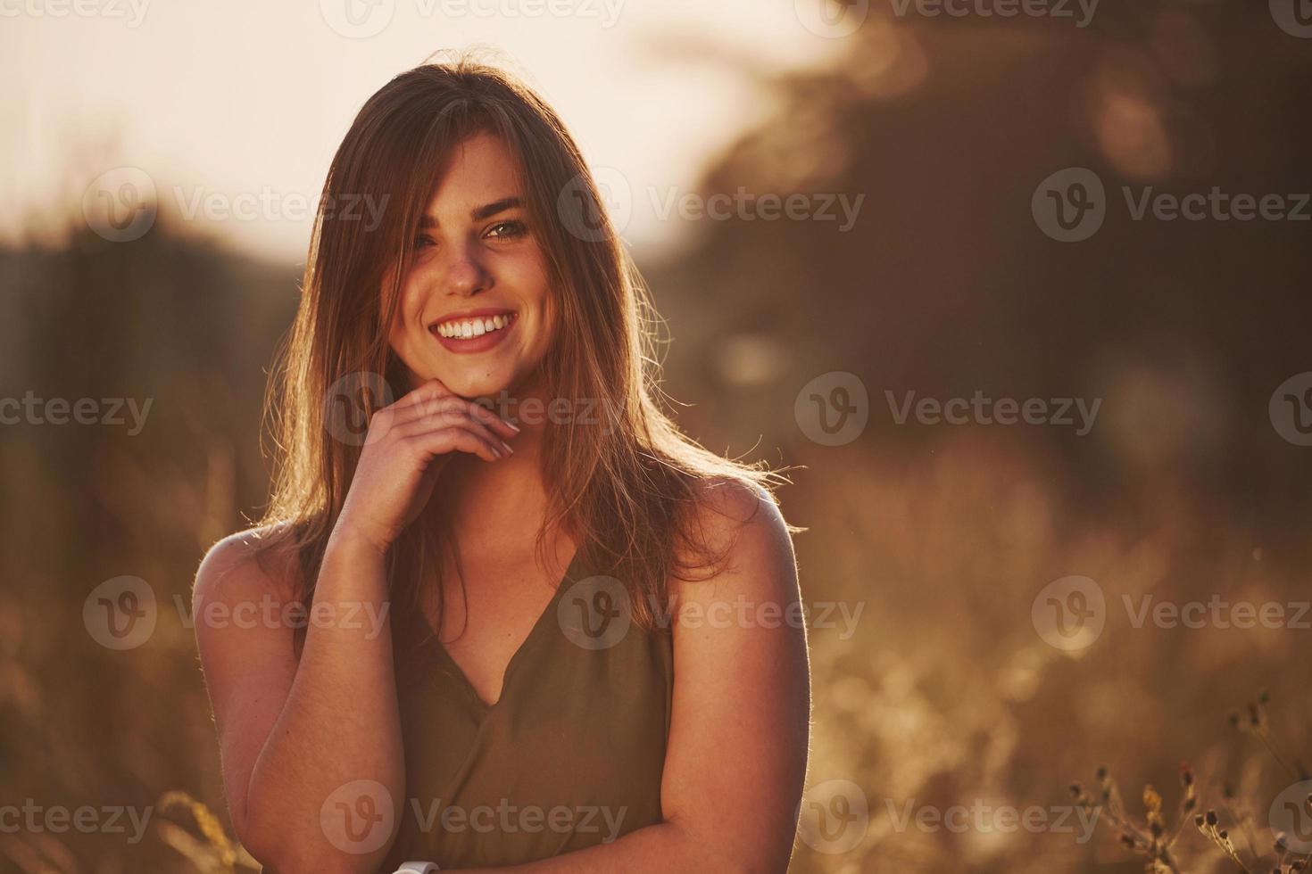 ritratto di contento ragazza quello in piedi nel il campo illuminato di luce del sole foto