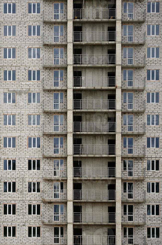 strutturato modello di un' russo pietra bianca Residenziale Casa edificio parete con molti finestre e balcone sotto costruzione foto