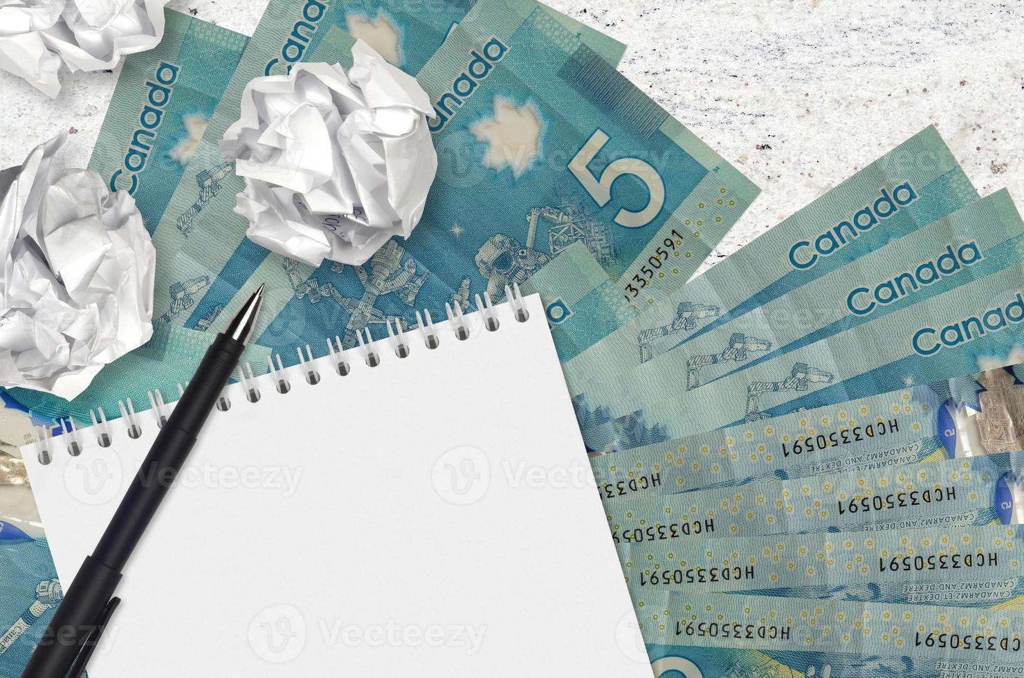 5 canadese dollari fatture e palle di spiegazzato carta con vuoto bloc notes. cattivo idee o Di meno di ispirazione concetto. ricerca idee per investimento foto