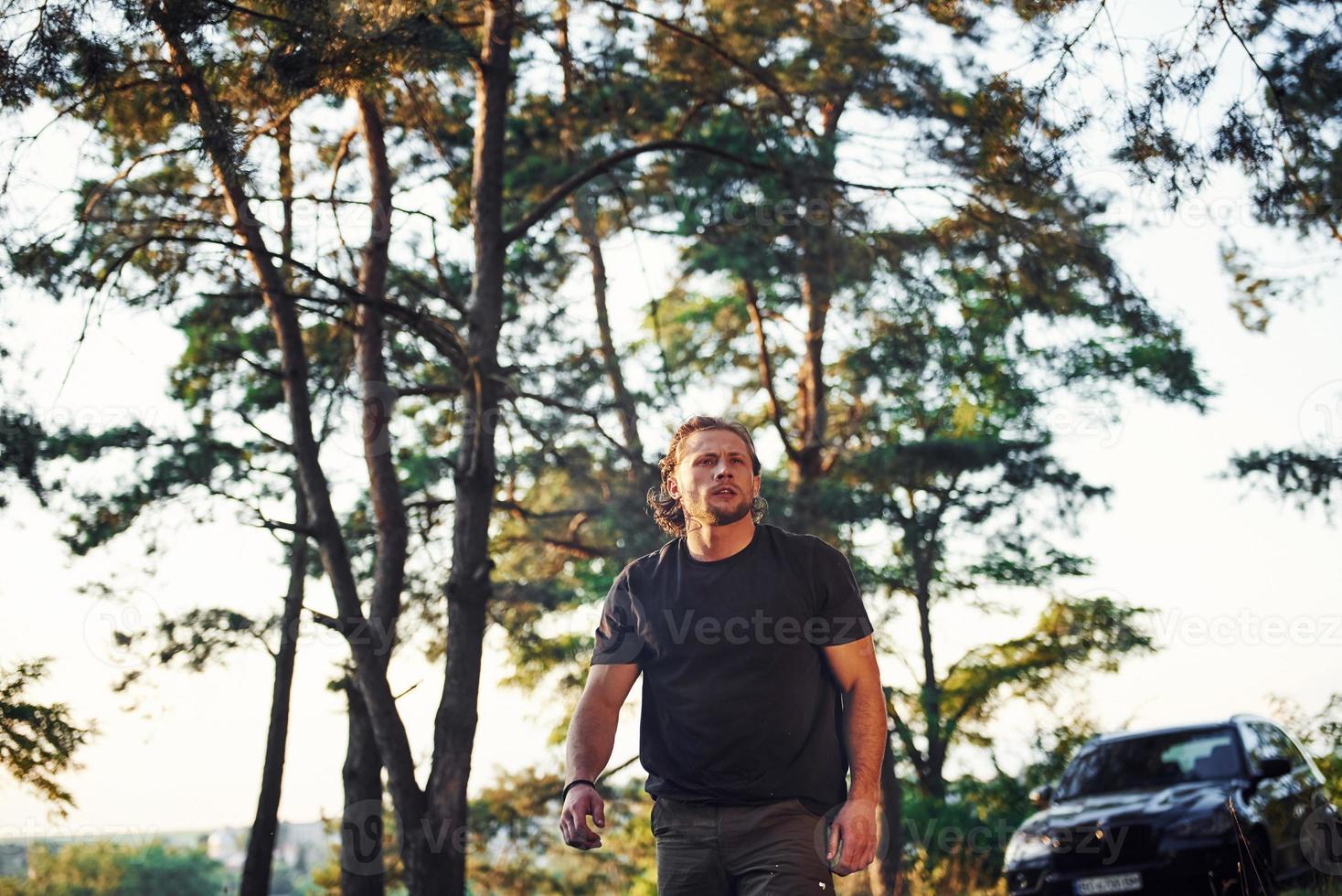 nero automobile dietro. ritratto di uomo quello sta nel il foresta e sembra a natura foto