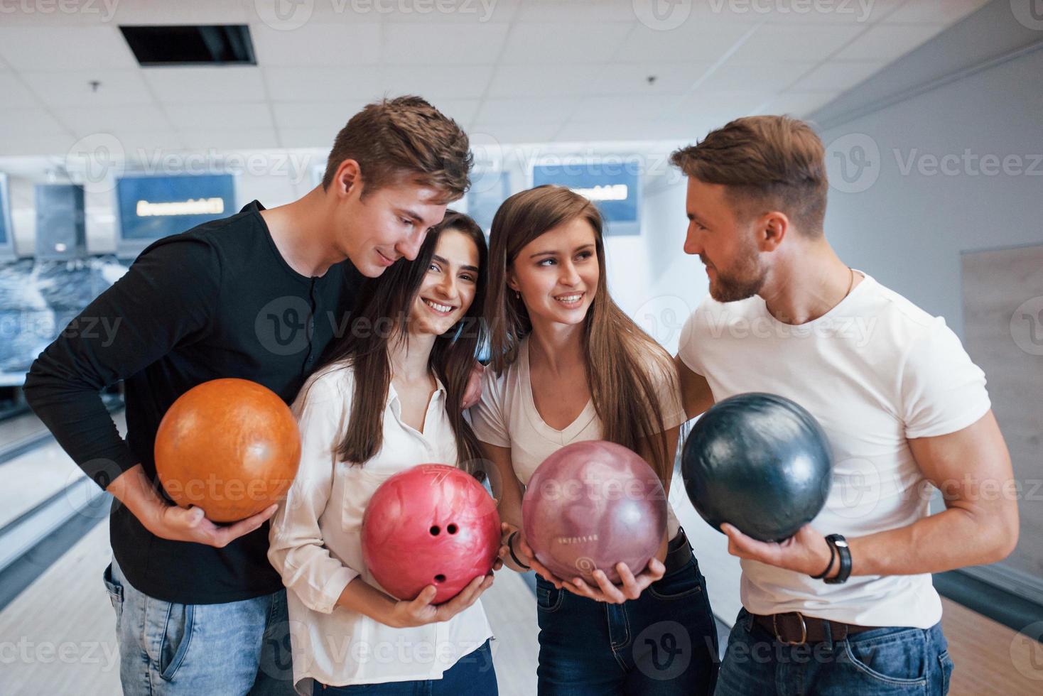 avendo conversazione. i giovani amici allegri si divertono al bowling club durante i fine settimana foto