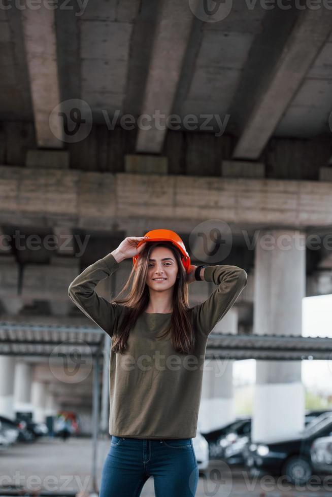 posa per la foto. ritratto di giovane e bella donna con casco di sicurezza in piedi sotto il ponte foto