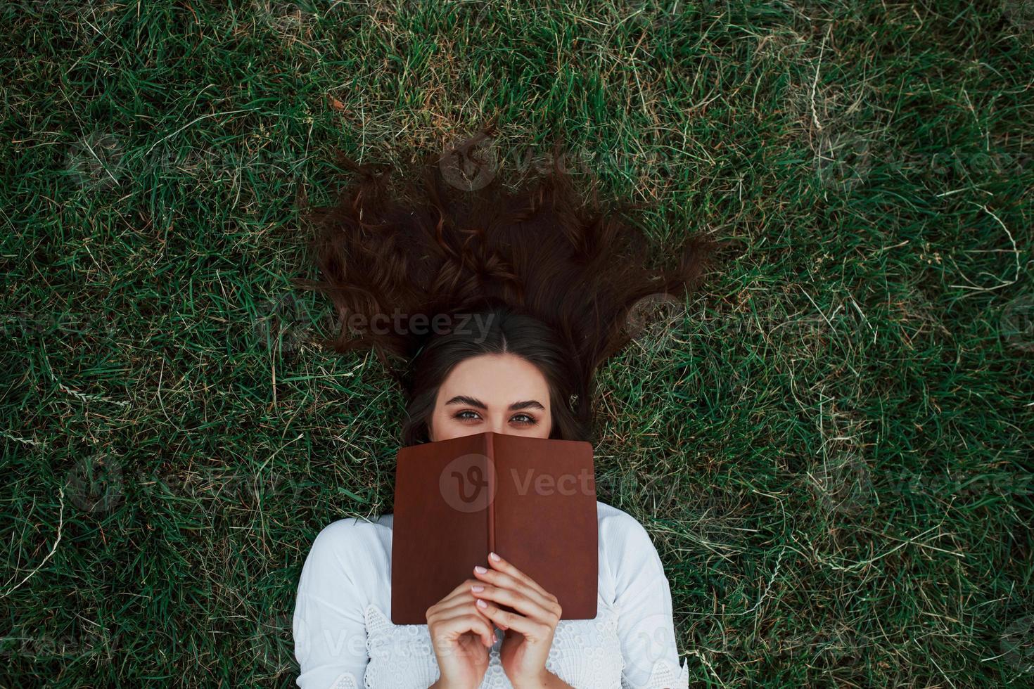 bellissimo capelli. ragazza dire bugie giù su il verde erba e avere un' riposo foto