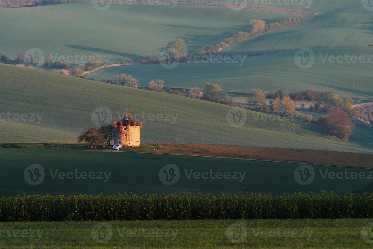 maestoso paesaggio di campo nel il sera. mulino a vento nel il centro di prato foto