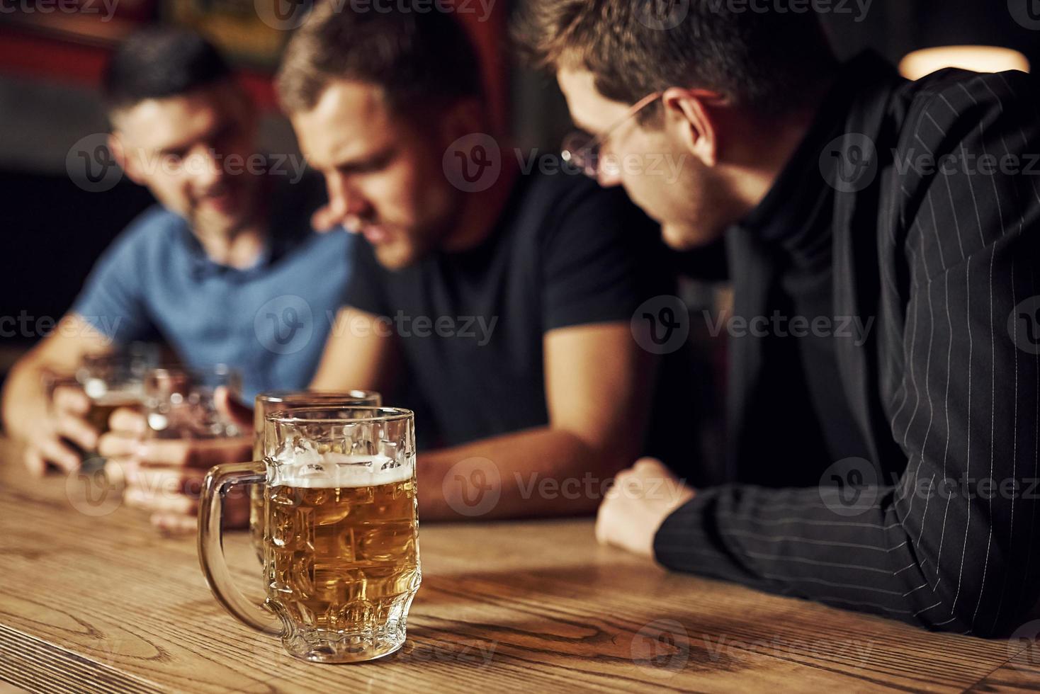 tre maschio amici nel il sbarra. supporto triste amico. unità di le persone. con birra su il tavolo foto