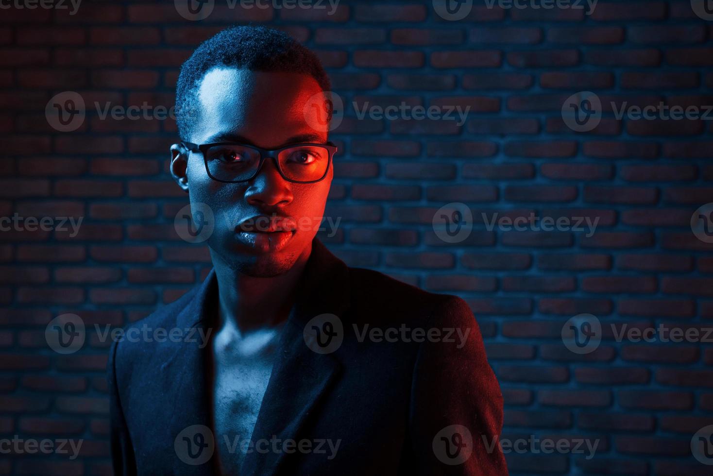 nel occhiali. futuristico neon illuminazione. giovane africano americano uomo nel il studio foto