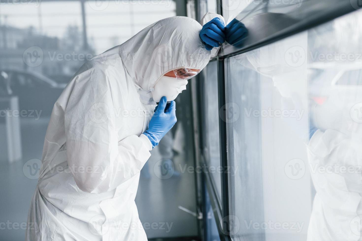 maschio medico scienziato nel laboratorio cappotto, difensiva occhiali e maschera si sente cattivo, esausto e malato foto