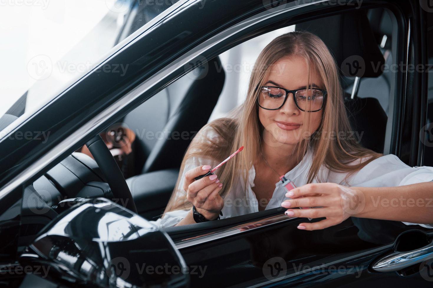 immagine nel movimento. bellissimo bionda ragazza seduta nel il nuovo auto con moderno nero interno foto