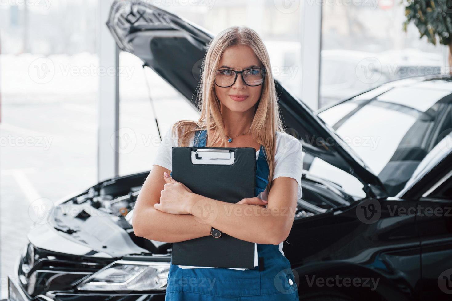 nuovo cliente è In arrivo. manager con bloc notes, nel il bianca camicia e blu uniforme sta contro automobile con cappuccio su foto