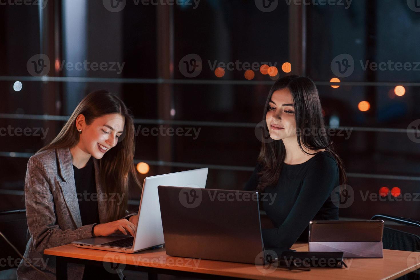 insieme a il stesso tavolo. squadra di giovane attività commerciale persone lavori su loro progetto a notte tempo nel il ufficio foto