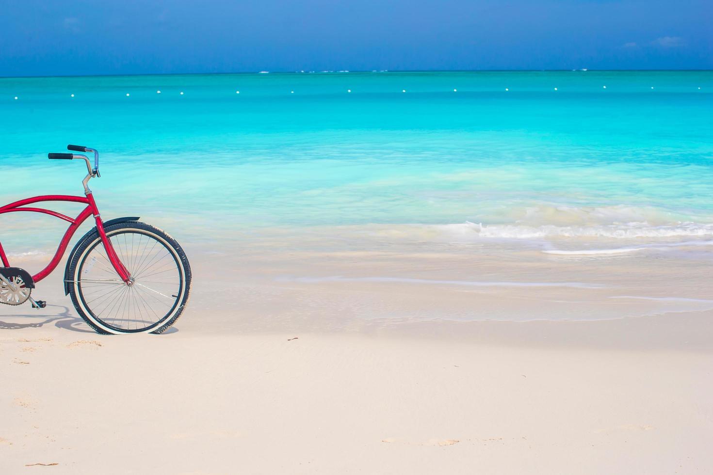 bici su una spiaggia tropicale contro l'oceano turchese e il cielo blu foto