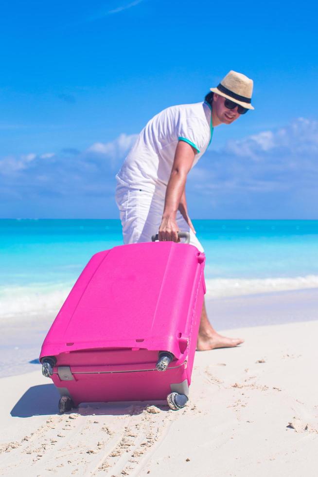 uomo che tira i suoi bagagli su una spiaggia tropicale foto