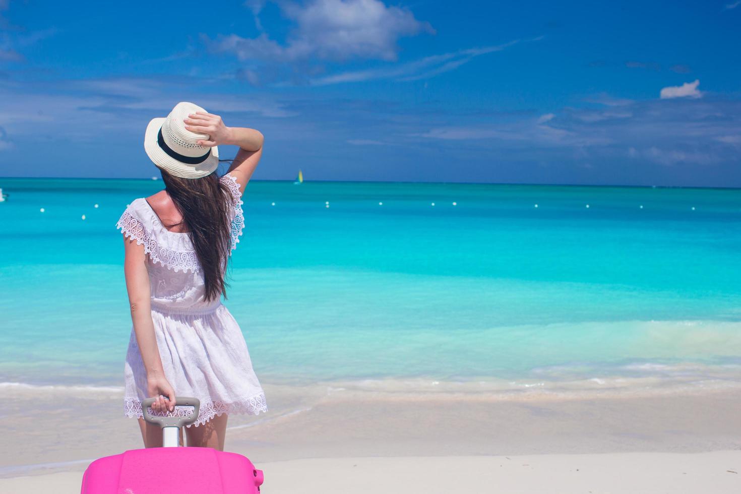 donna che tira una valigia su una spiaggia foto