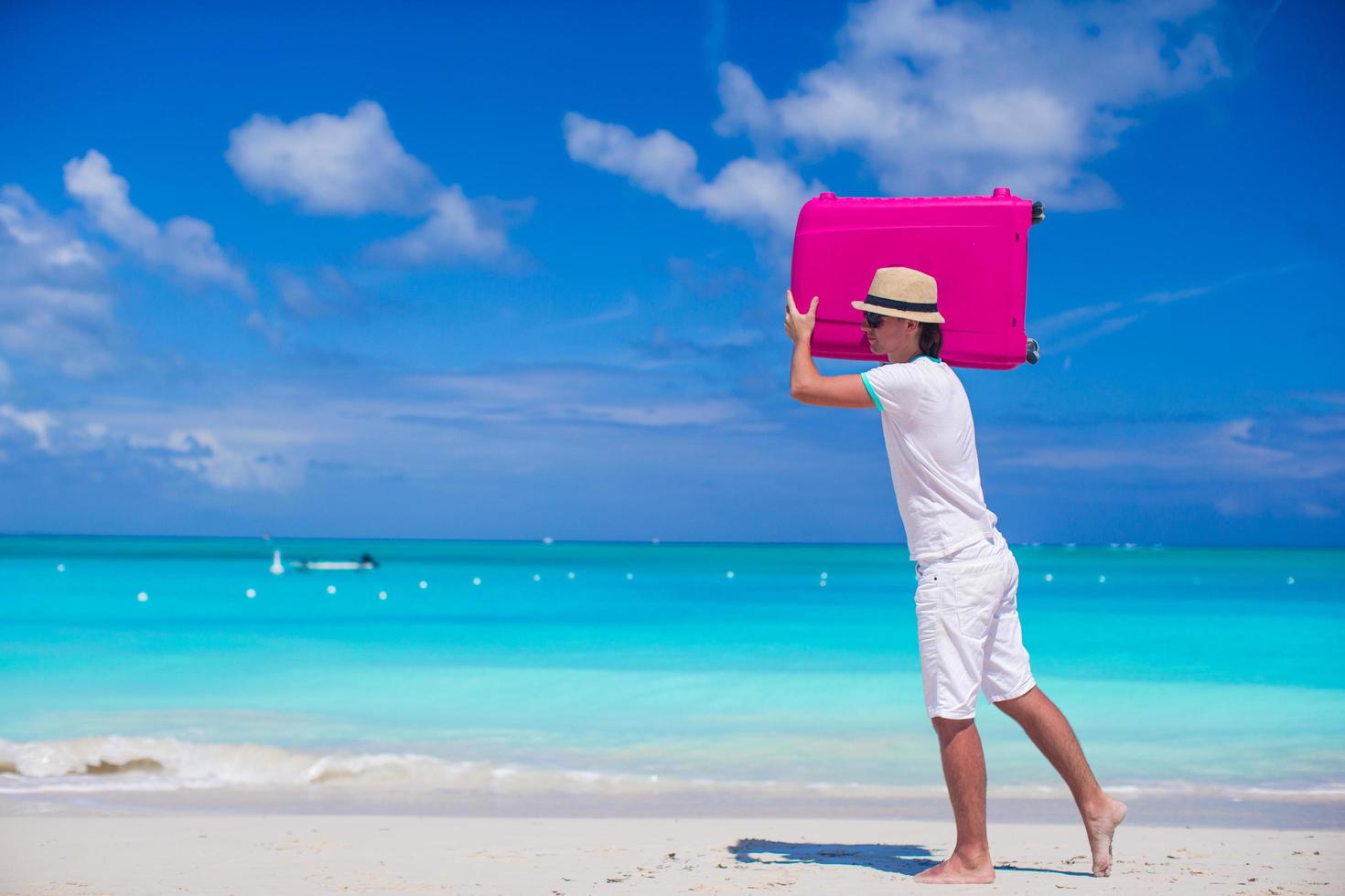 uomo che trasporta una valigia su una spiaggia foto