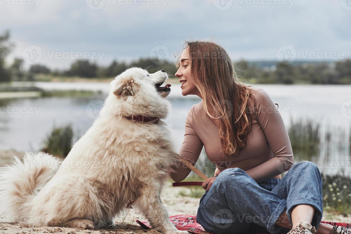 bello cane. bionda ragazza con sua carino bianca animale domestico avere un' grande tempo la spesa su un' spiaggia foto