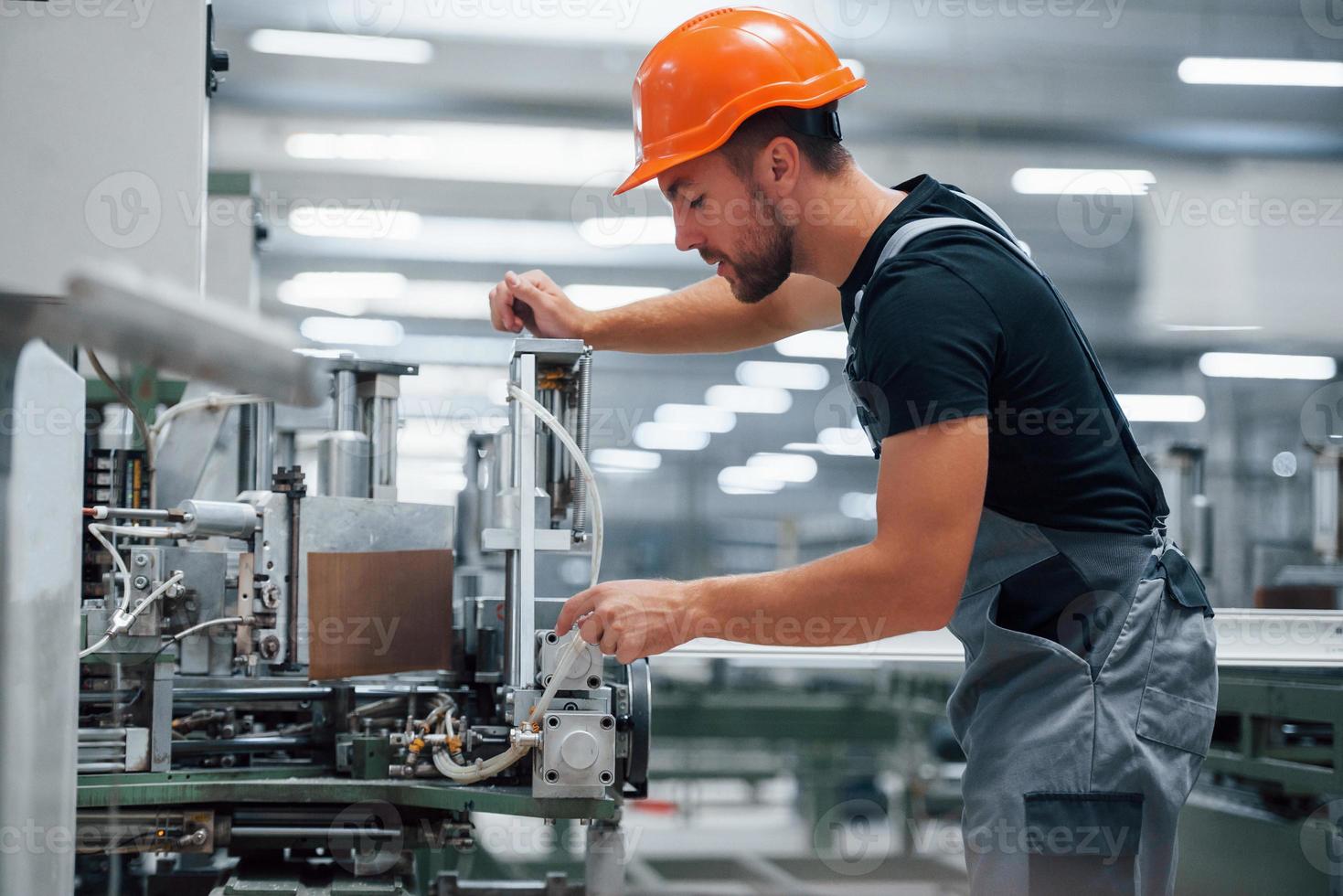operatore di macchina. industriale lavoratore in casa nel fabbrica. giovane tecnico con arancia difficile cappello foto