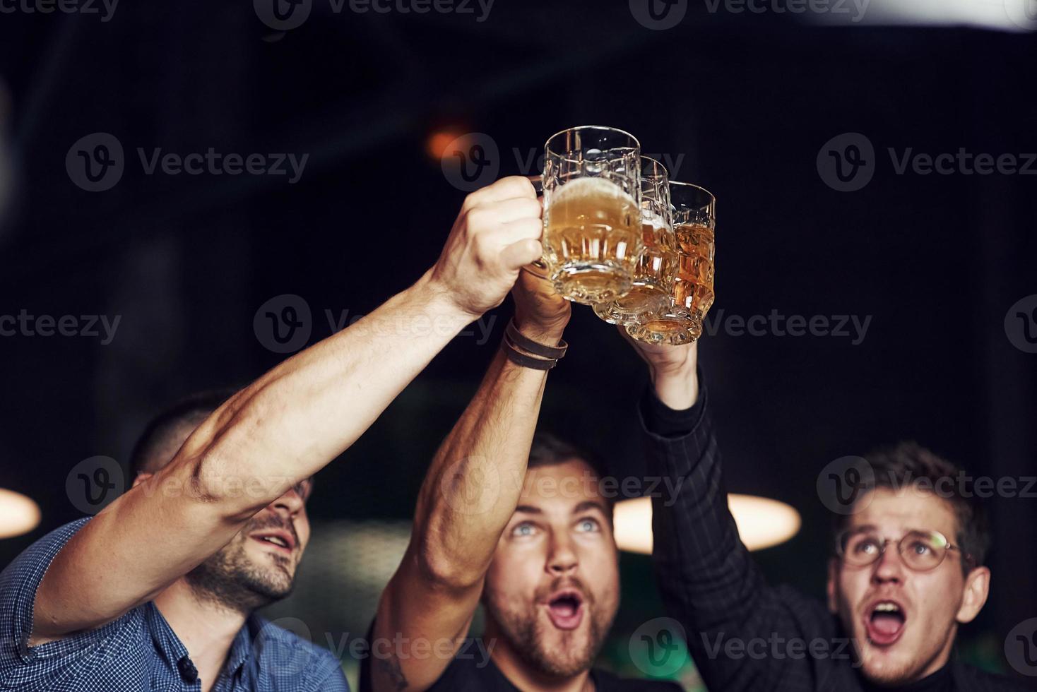 colpi occhiali. tre gli sport fan nel un' bar Guardando calcio. con birra nel mani foto