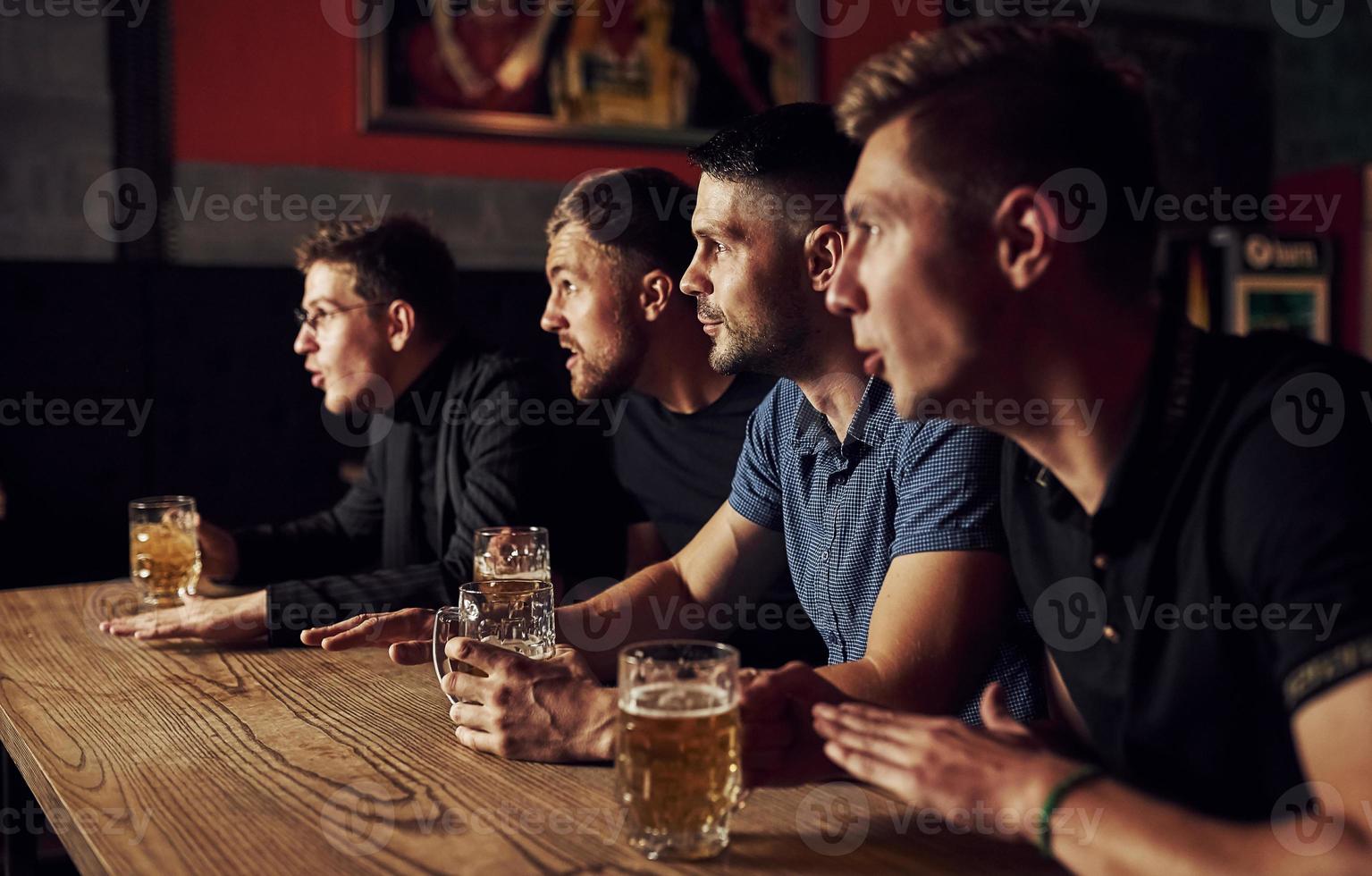 tre gli sport fan nel un' bar Guardando calcio. con birra nel mani foto