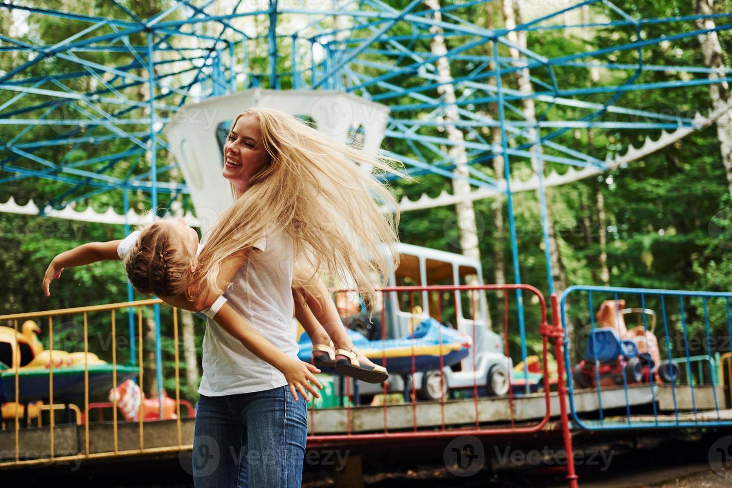 allegro poco ragazza sua madre avere un' bene tempo nel il parco insieme vicino attrazioni foto