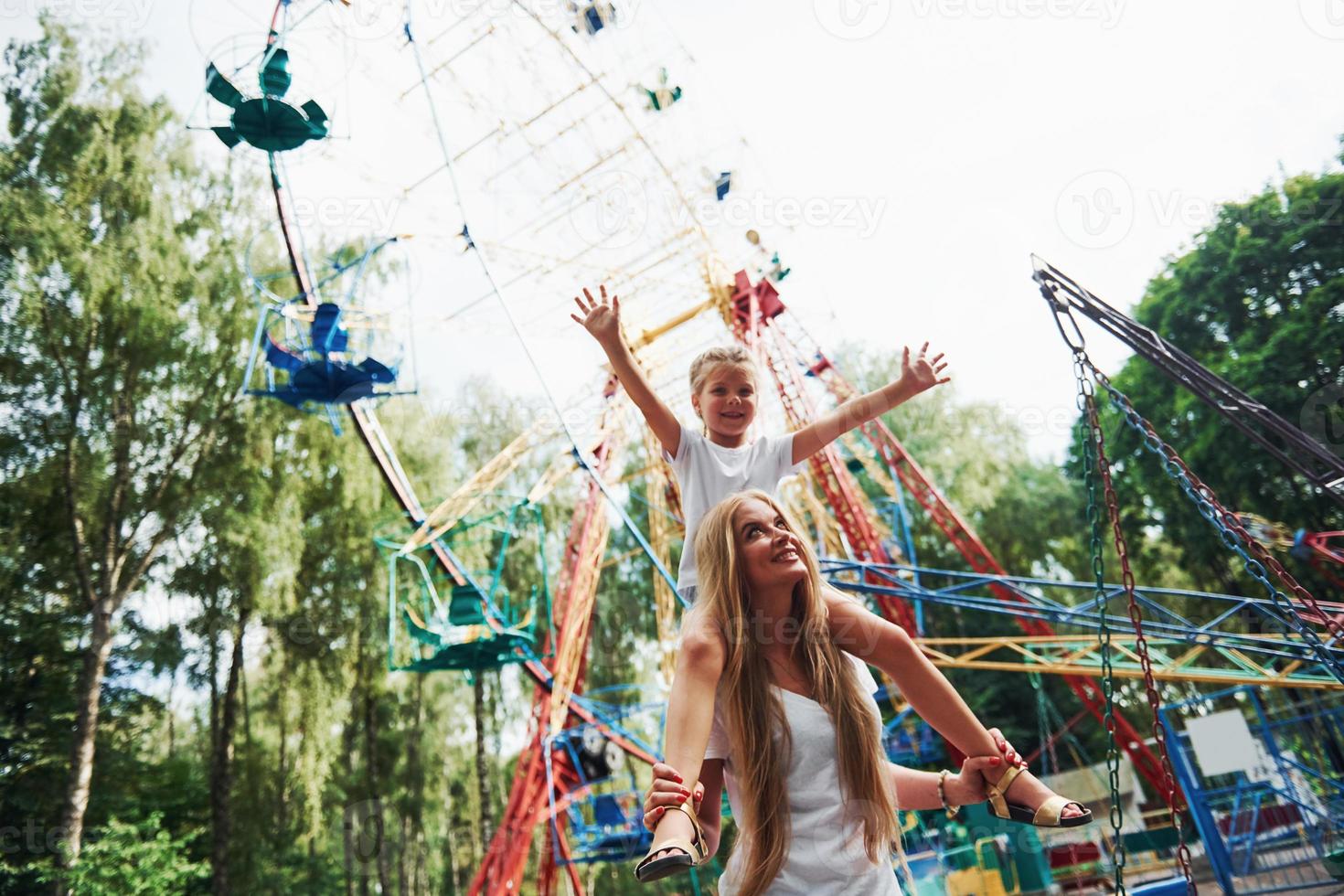 allegro poco ragazza sua madre avere un' bene tempo nel il parco insieme vicino attrazioni foto