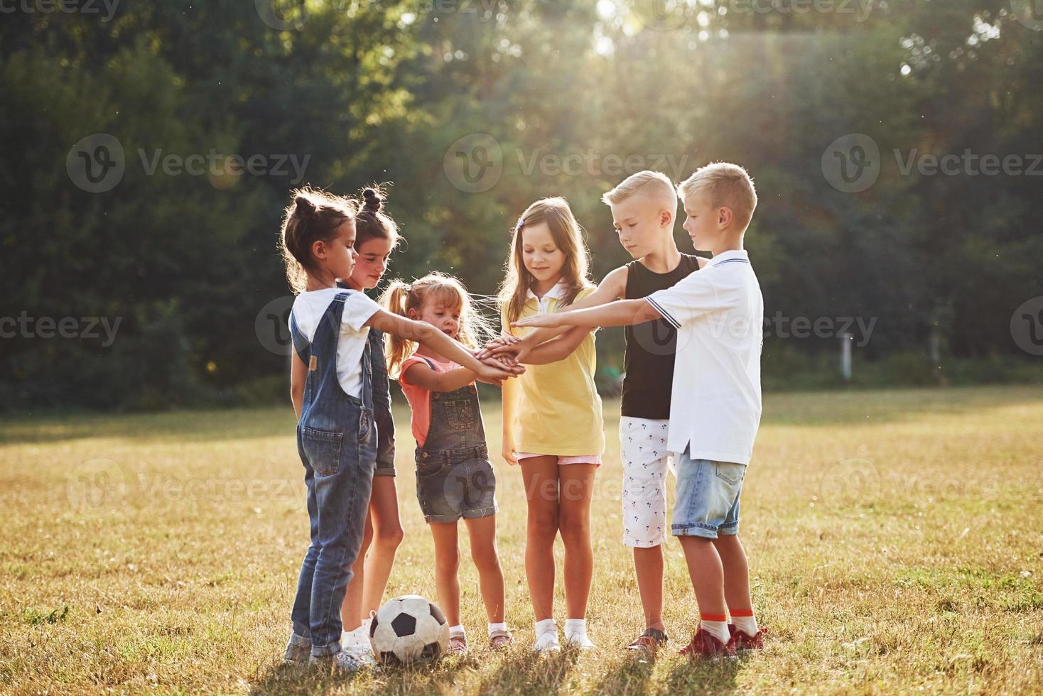 pronto per il gioco. giovane allegro bambini con calcio palla sta insieme nel il campo a soleggiato giorno foto