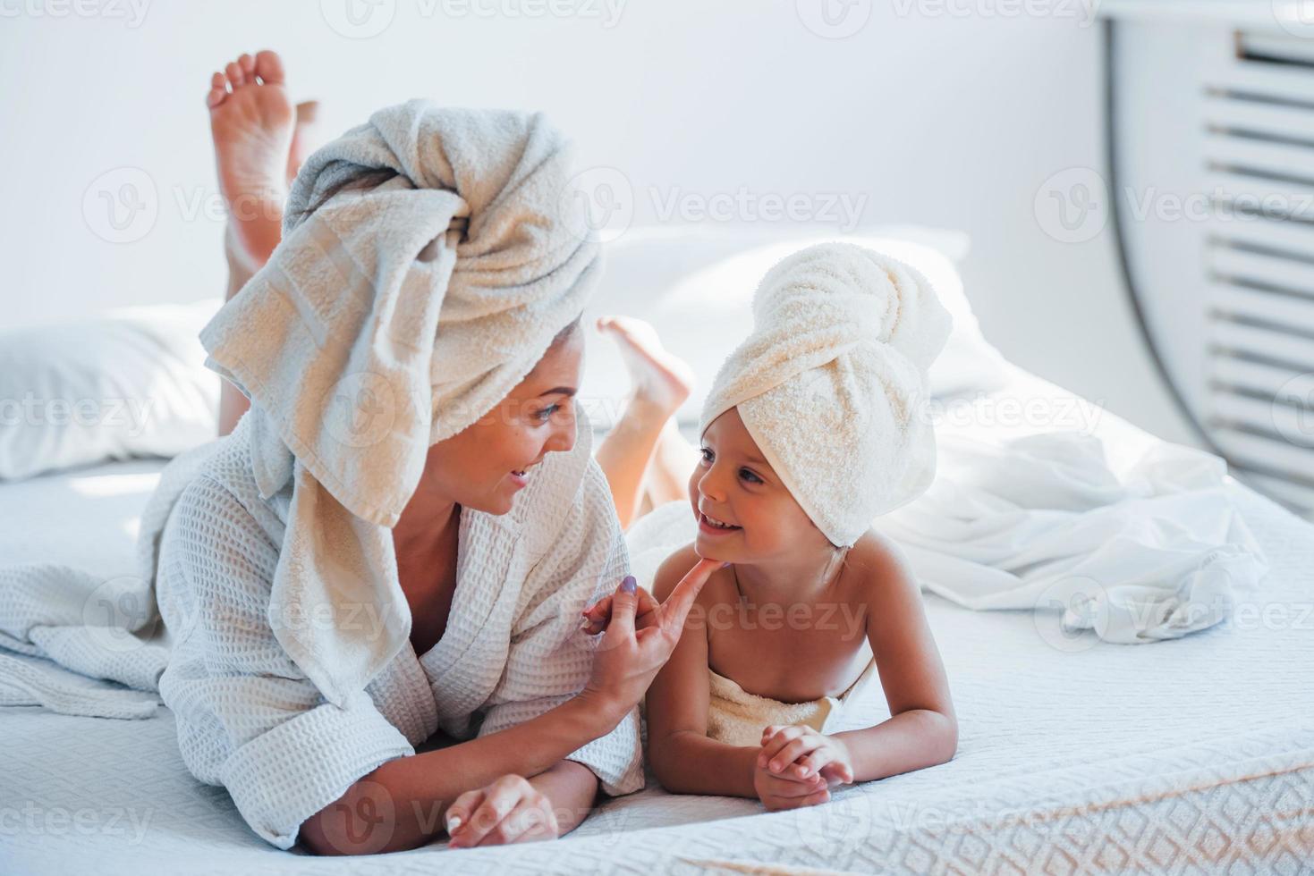 giovane madre con sua figlia avere bellezza giorno in casa nel bianca camera foto