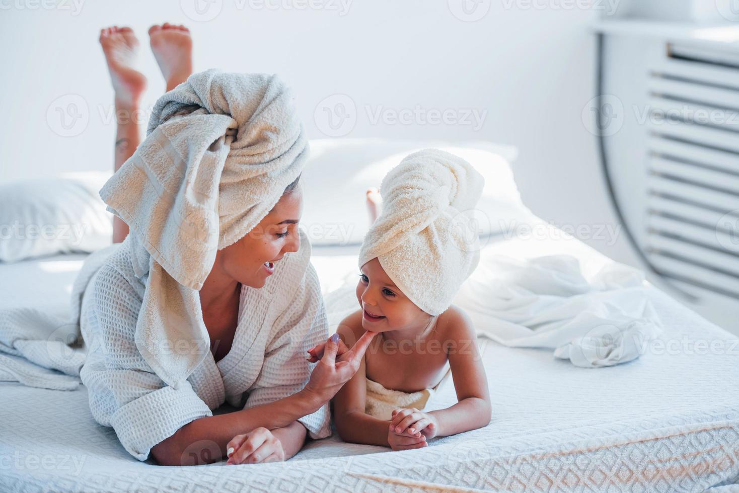 giovane madre con sua figlia avere bellezza giorno in casa nel bianca camera foto