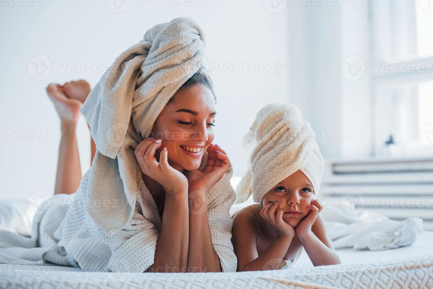 avendo divertimento. giovane madre con sua figlia avere bellezza giorno in casa nel bianca camera foto