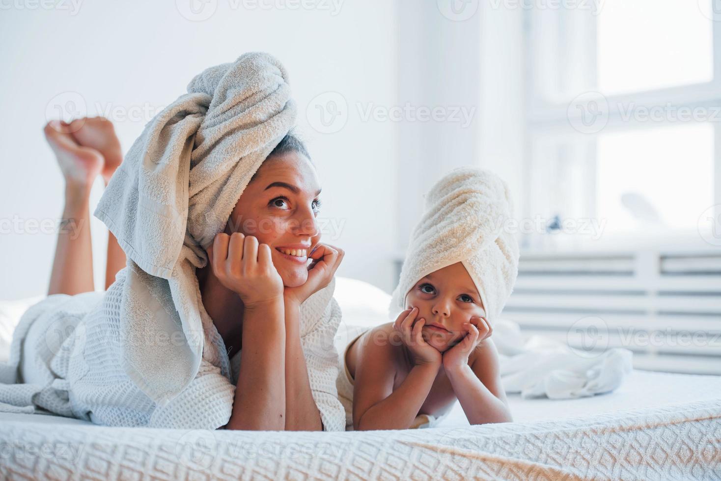 avendo divertimento. giovane madre con sua figlia avere bellezza giorno in casa nel bianca camera foto