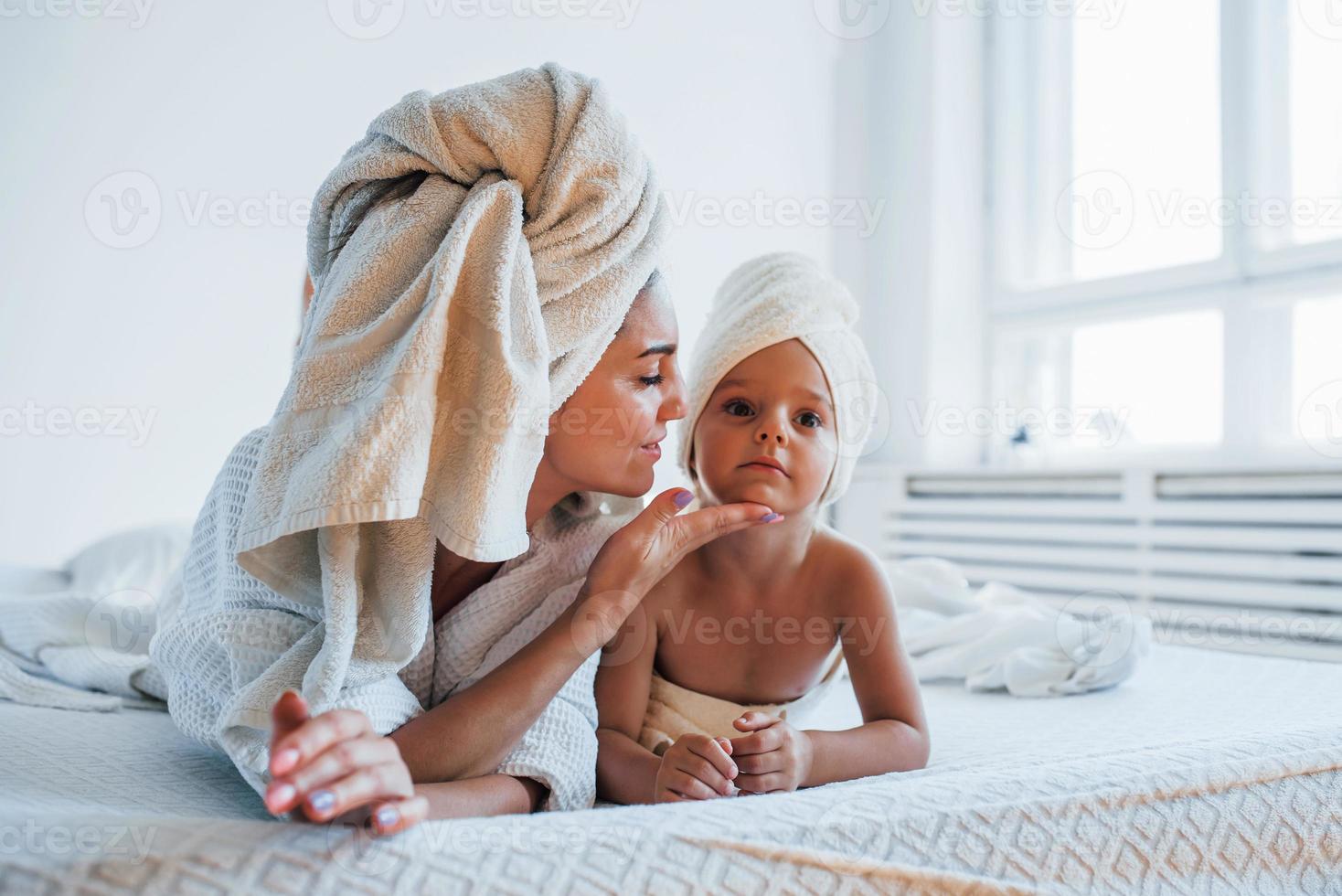 avendo divertimento. giovane madre con sua figlia avere bellezza giorno in casa nel bianca camera foto