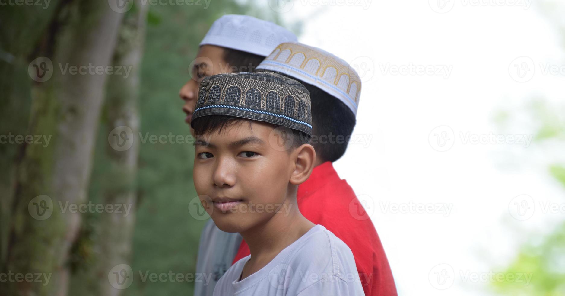 ritratto asiatico musulmano o islamico ragazzi in piedi insieme nel davanti di albero e in attesa per fare il religioso attività a scuola, morbido e selettivo messa a fuoco. foto