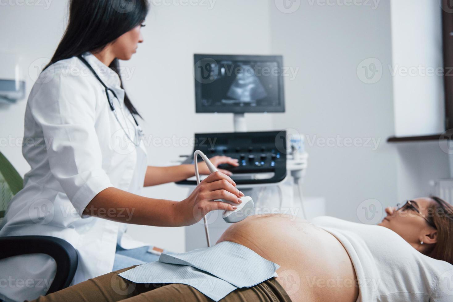 femmina medico fa ultrasuono per un' incinta donna nel il ospedale foto