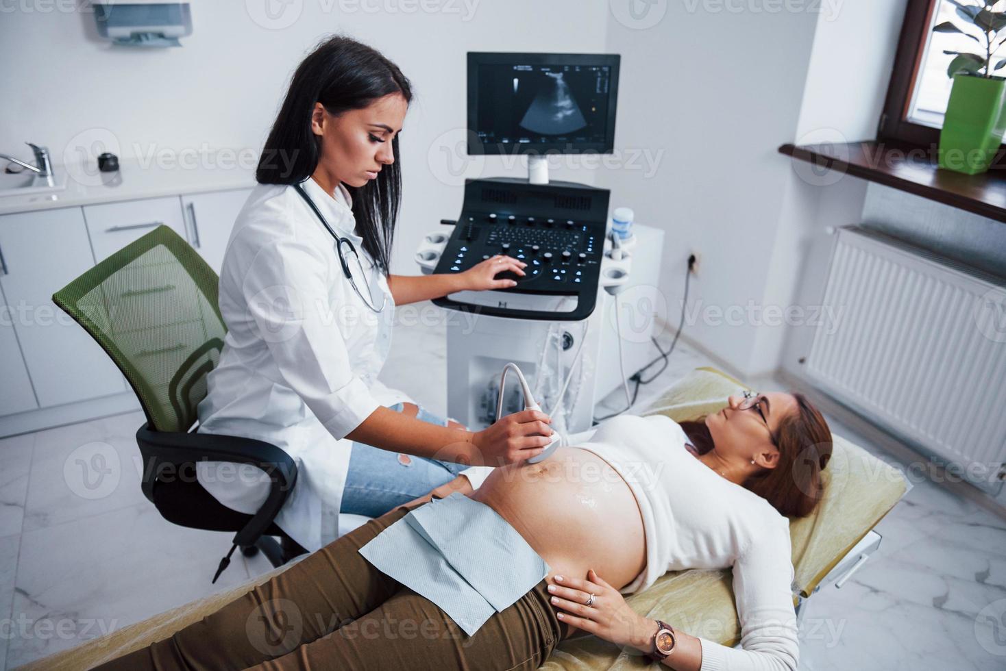femmina medico fa ultrasuono per un' incinta donna nel il ospedale foto