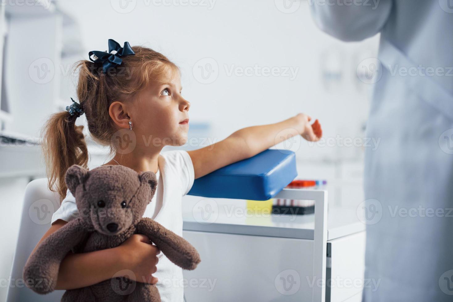 preparazione per sangue campionamento. poco ragazza con sua giocattolo nel mani è nel il clinica foto