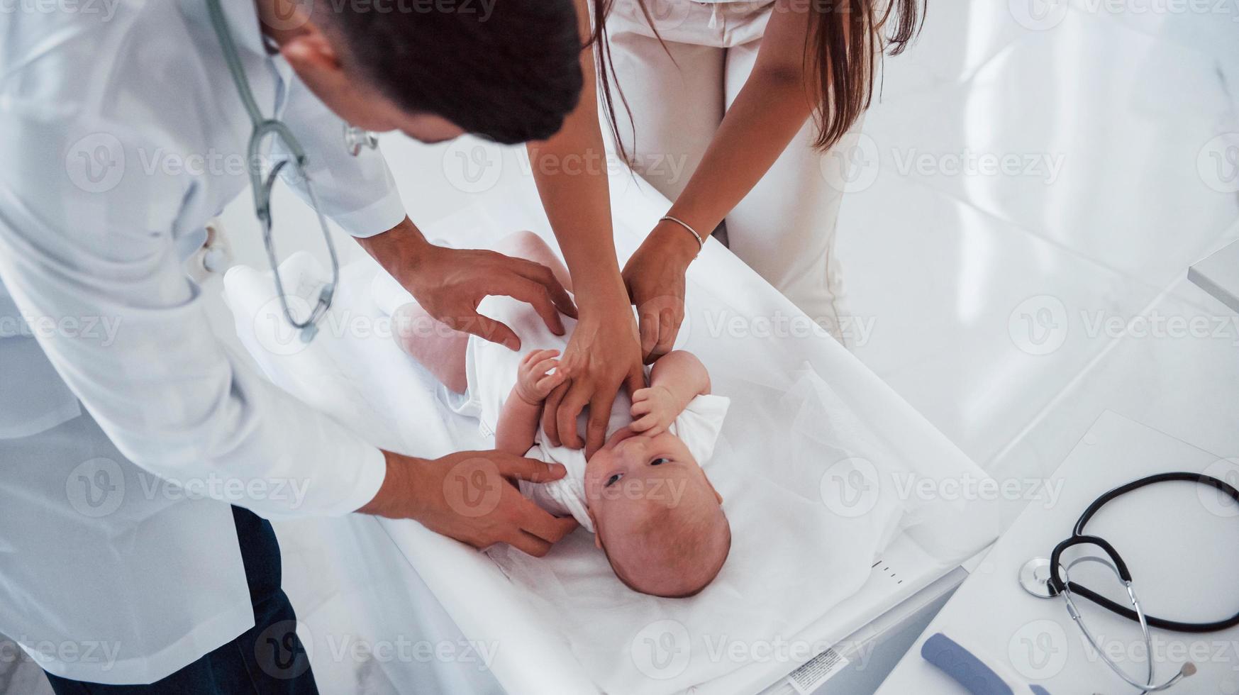 giovane pediatra è con poco bambino nel il clinica a giorno foto