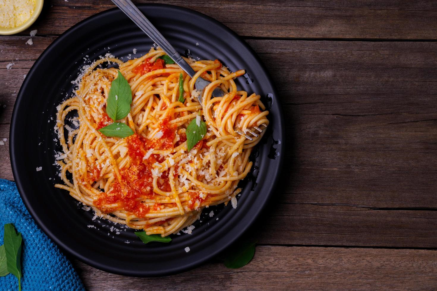 delizioso spaghetti pasta con gamberi e formaggio servito su un' nero piatto su un' di legno tavolo italiano ricetta pomodoro salsa la verdura, e spezie superiore Visualizza con copia spazio foto