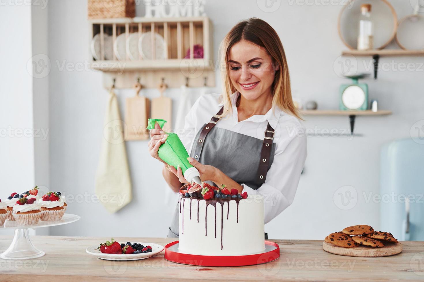 scrosciante crema. donna sta in casa nel il cucina con fatti in casa torta foto