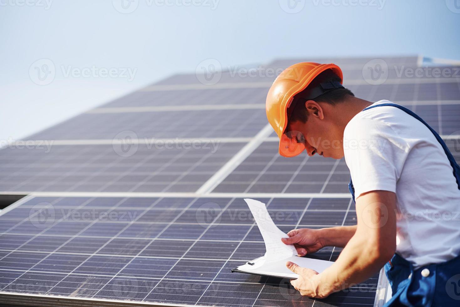 con documenti. maschio lavoratore nel blu uniforme all'aperto con solare batterie a soleggiato giorno foto