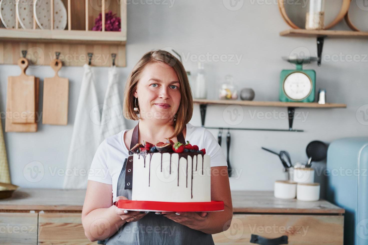 donna sta in casa nel il cucina con fatti in casa torta nel sua mani foto