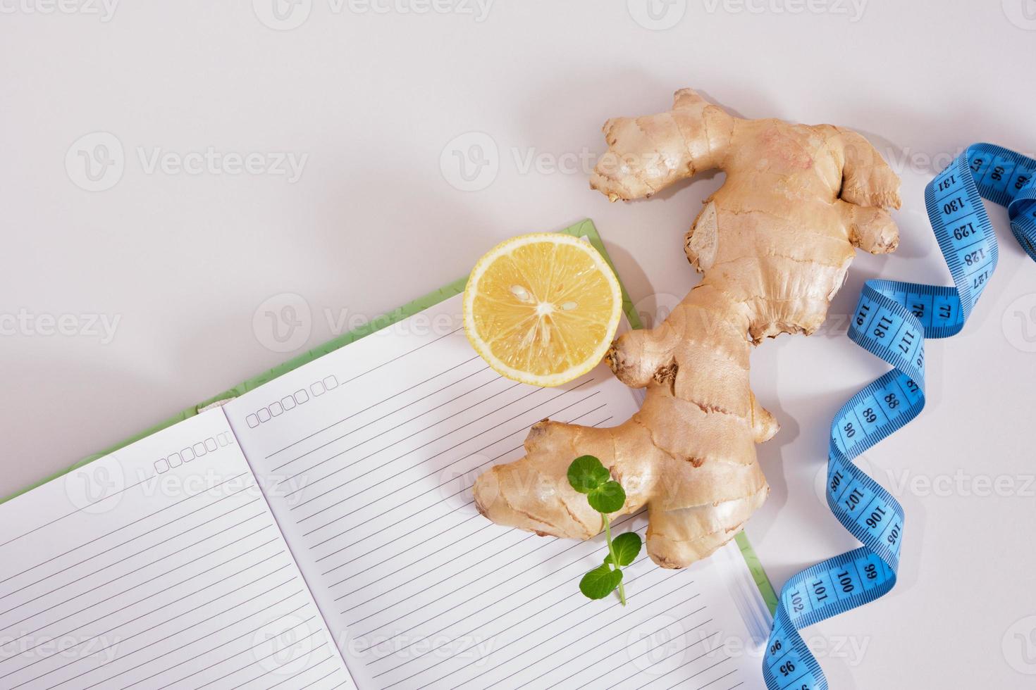 misurazione nastro, Zenzero, Limone, menta le foglie e bloc notes su grigio sfondo, prodotti ardente Grasso e calorie concetto foto