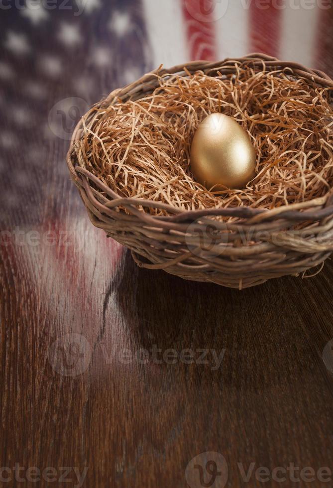 d'oro uovo nel nido con americano bandiera riflessione su tavolo foto