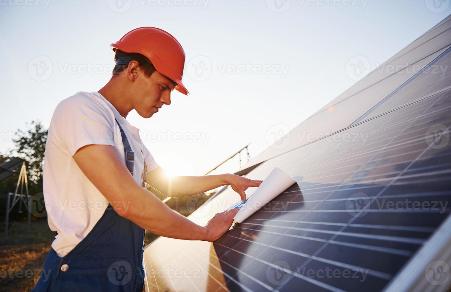 bellissimo luce del sole. maschio lavoratore nel blu uniforme all'aperto con solare batterie foto