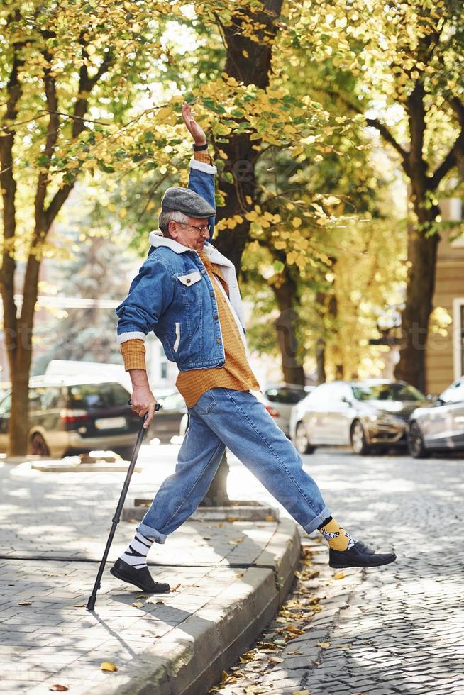 contento elegante anziano nel alla moda Abiti e nel bicchieri avere un' camminare e godendo vita foto