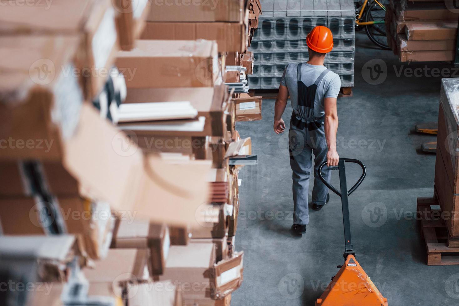 superiore Visualizza di maschio lavoratore nel magazzino con pallet camion foto