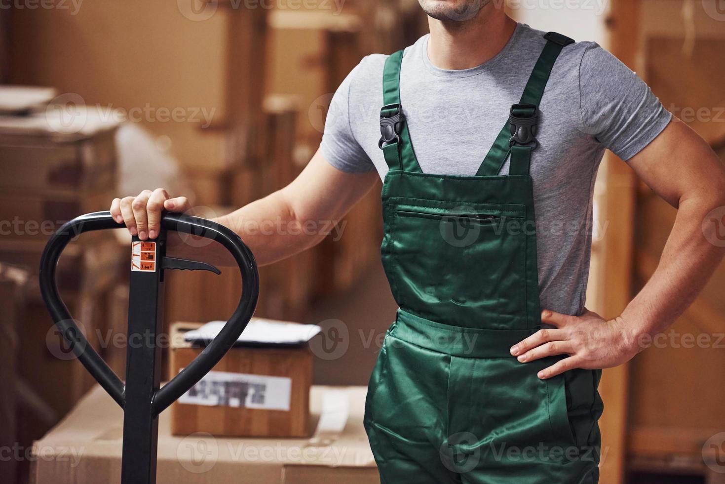 giovane maschio lavoratore nel uniforme è nel il magazzino con pallet camion foto