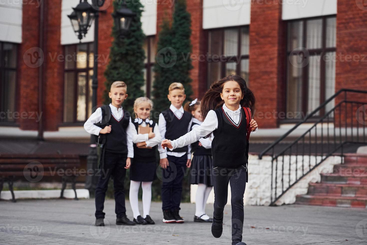 gruppo di bambini nel scuola uniforme in posa per il telecamera all'aperto insieme vicino formazione scolastica edificio foto