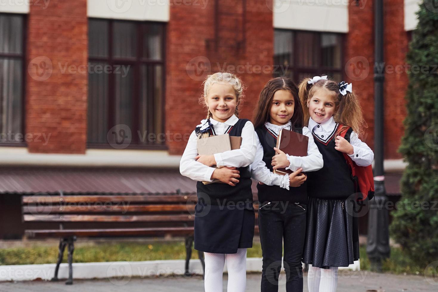 gruppo di femmina bambini nel scuola uniforme quello è all'aperto insieme vicino formazione scolastica edificio foto
