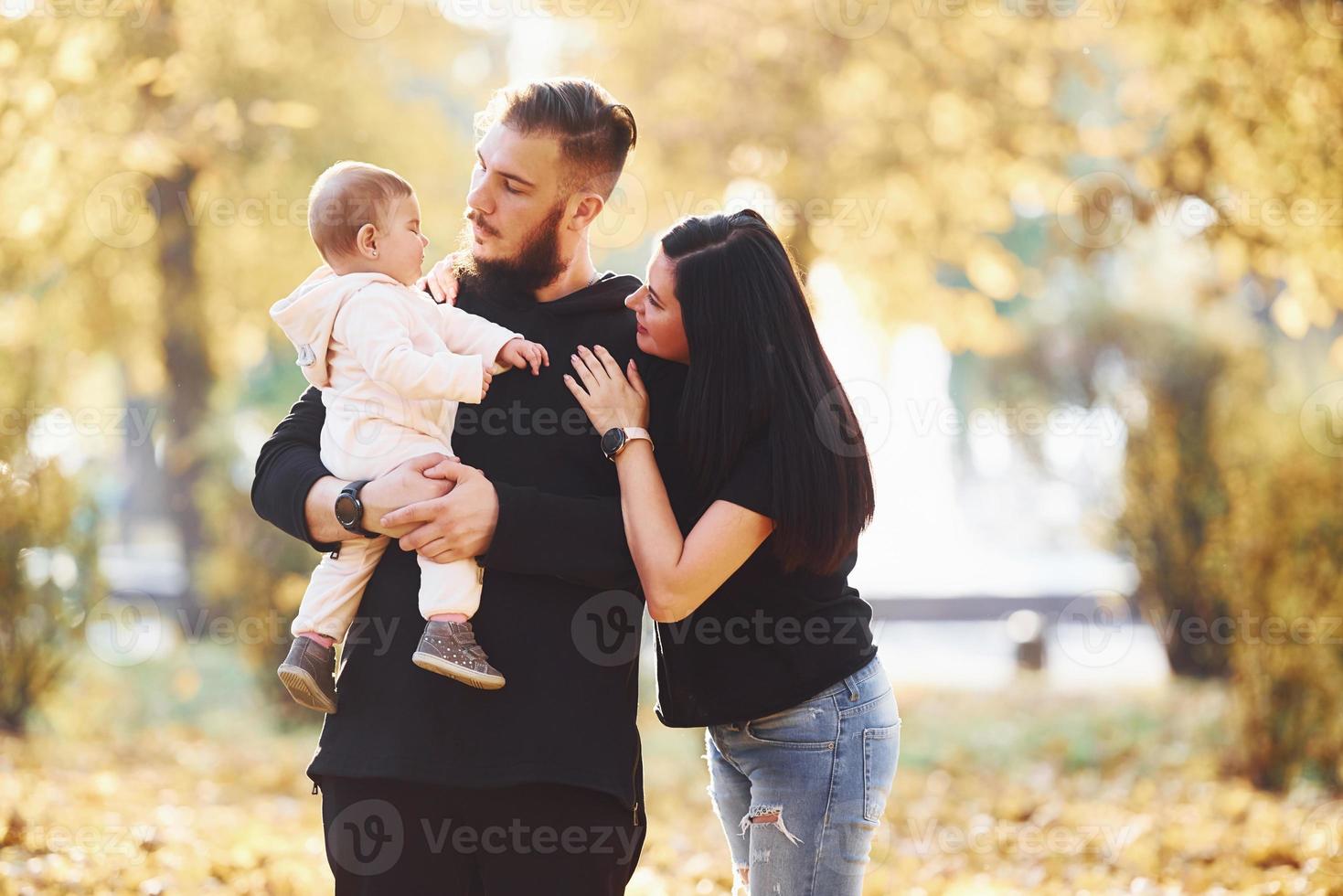 allegro famiglia avendo divertimento insieme con loro bambino nel bellissimo autunno parco foto