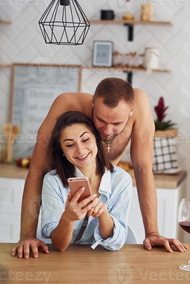 coppia insieme nel il cucina a mattina tempo con mobile Telefono foto