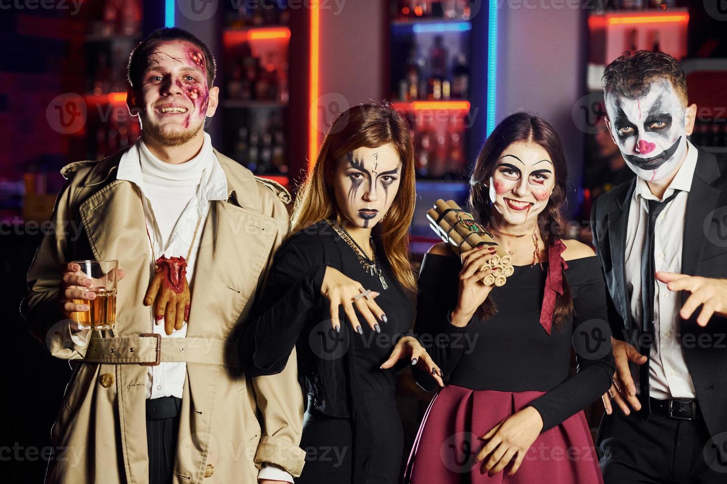 amici è su il tematico Halloween festa nel pauroso trucco e costumi avere divertimento e in posa per il telecamera insieme foto